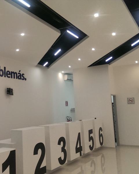 Sucursal Cablemás terminada, con plafón de luces lineales y mostradores blancos numerados