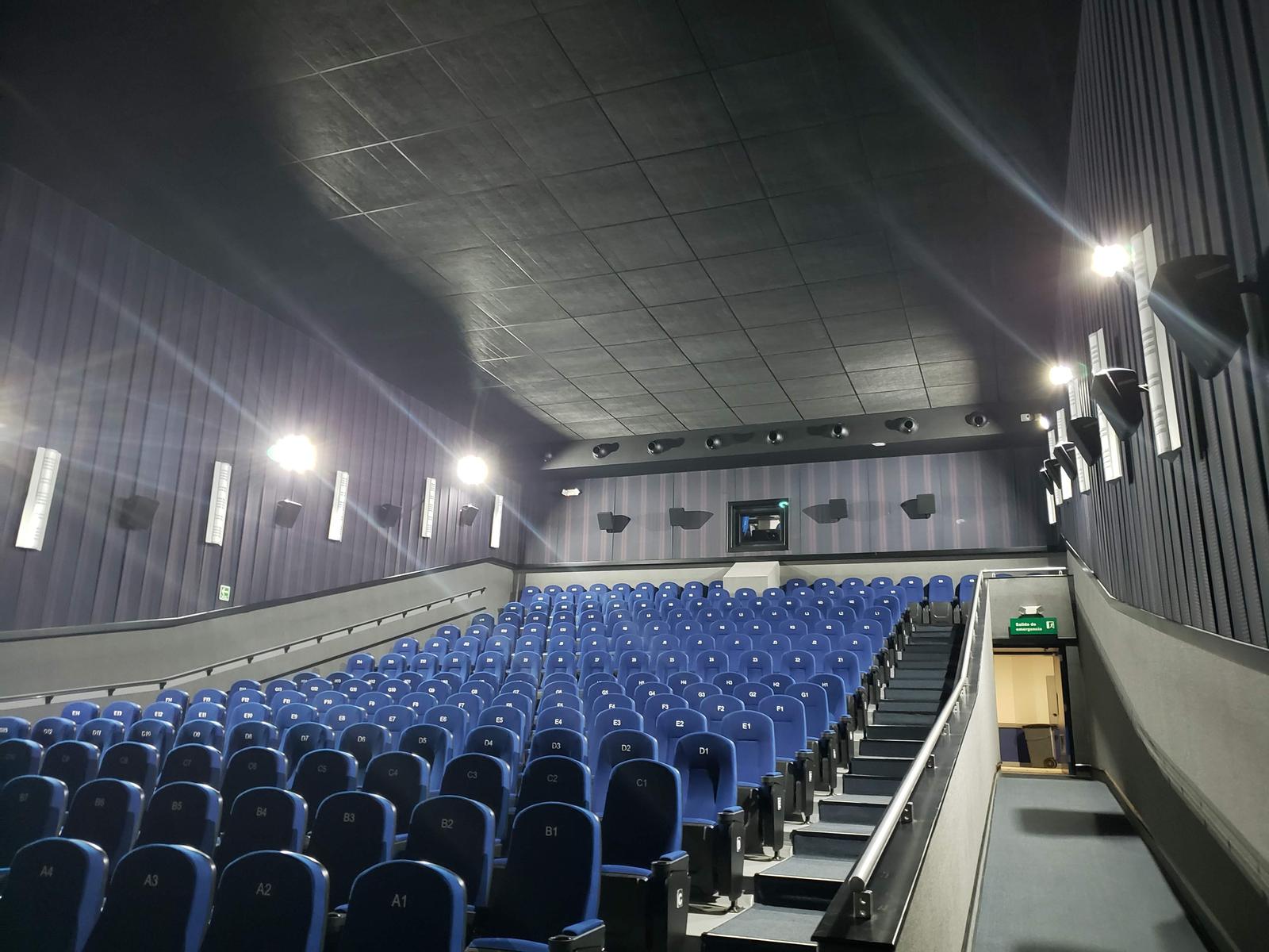 Sala de cine terminada con butacas azules y muros acústicos